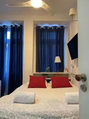 a bedroom with blue curtains and a bed with red pillows at Linha 22 in Porto