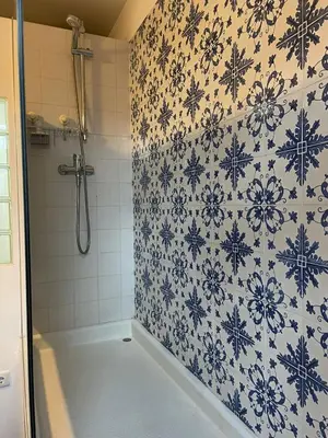 a bathroom with a shower with blue and white tiles at Linha 22 in Porto