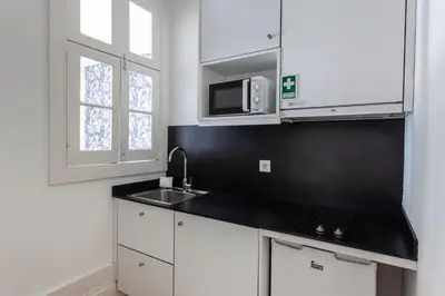 a kitchen with white cabinets and a sink and a microwave at Citybreak-apartments Lapa in Porto