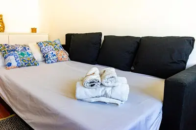 a bed with towels on it with a couch at Guest H4U - Porto Batalha City Center in Porto