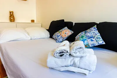 a bed with towels on it with a couch at Guest H4U - Porto Batalha City Center in Porto