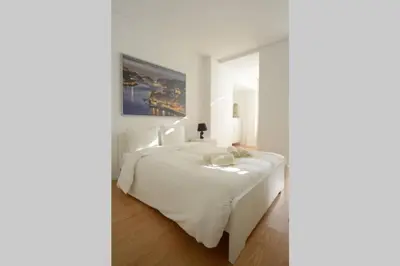 a bedroom with a white bed with a painting on the wall at Softly Porto in Porto