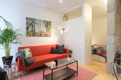 a living room with a red couch and a table at LovelyStay - Vitoria Viewpoint 1BR Flat in Porto