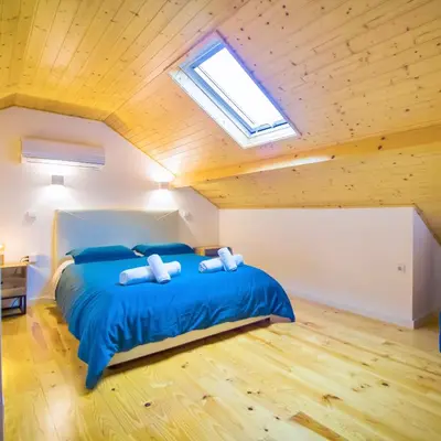 a bedroom with a bed with blue sheets and a skylight at Porto Domus 210 Duplex in Porto