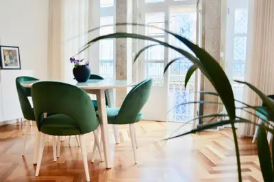a dining room table with green chairs and a potted plant at OHH - Caldeireiros Luxury Apartments in Porto