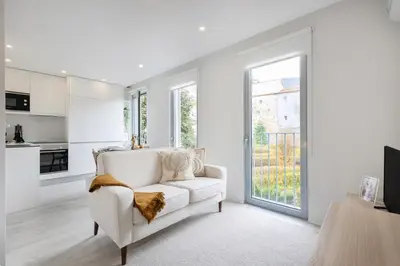 a living room with a white couch and a large window at Modern Studio @ Palácio de Cristal in Porto