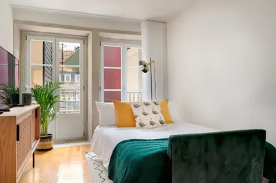 a bedroom with a bed with a green blanket on it at FLORES PLAZA APARTMENT in Porto
