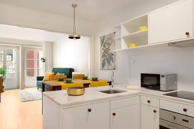 a kitchen with white cabinets and a living room at FLORES PLAZA APARTMENT in Porto