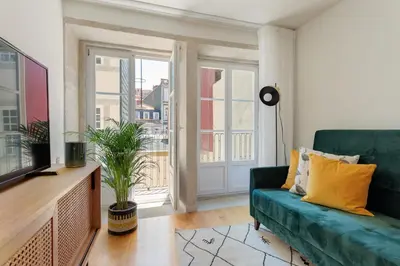 a living room with a green couch and a window at FLORES PLAZA APARTMENT in Porto