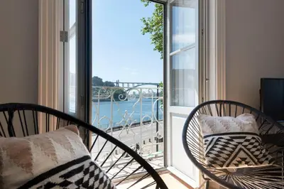 a balcony with two chairs and a view of the water at Quayside Douro River in Porto