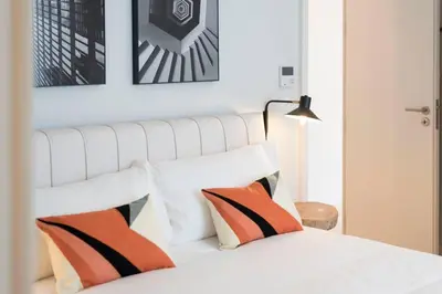 a white bed with orange and black pillows on it at Quayside Douro River in Porto