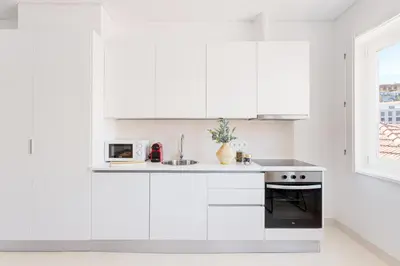 a white kitchen with white cabinets and a sink at Oporto Amazing View Apartment in Porto