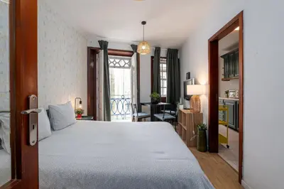 a table with a lamp on it next to a bed at Renovated Feb25 Clerigos Cozy Balcony with self check in in Porto