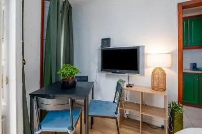 a bedroom with a bed and a flat screen tv at Renovated Feb25 Clerigos Cozy Balcony with self check in in Porto