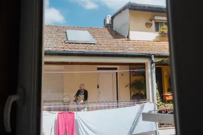 a man standing on the balcony of a house drying his clothes at House Romantic R/C Right in Porto
