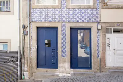 two blue doors on the side of a building at Vitória over the roofs II in Porto