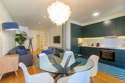 a kitchen and living room with a glass table and white chairs at Chic Alves Apartment in Porto