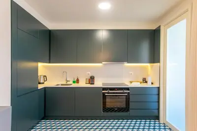 a kitchen with dark green cabinets and a sink at Chic Alves Apartment in Porto