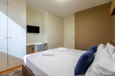 a bedroom with a large white bed and a tv at Chic Alves Apartment in Porto