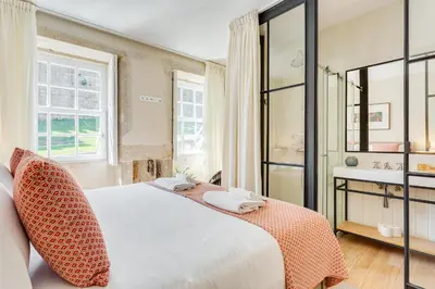 a bedroom with a white bed and a bathroom at Jardins da Muralha Apartments by DA'HOME in Porto