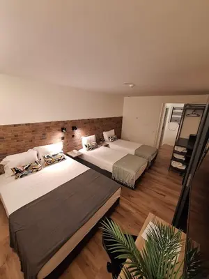 two beds in a large room with wooden floors at Hotel Portucalense in Porto