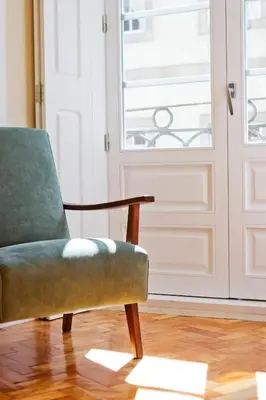 a green chair sitting in front of a door at Ribeira - Dixos Oporto Apartments IV in Porto