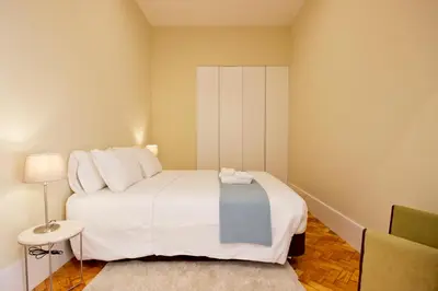 a bedroom with a large white bed and a chair at Ribeira - Dixos Oporto Apartments IV in Porto