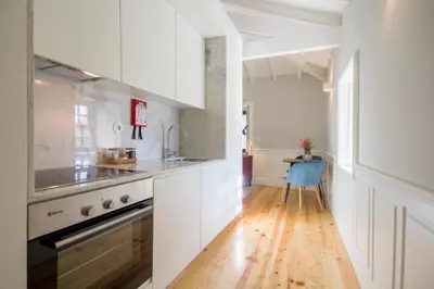 a kitchen with white cabinets and a wooden floor at Porto Toja Apartments in Porto