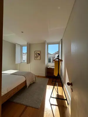 a bedroom with a bed and two windows at Guest House Arca de Água in Porto