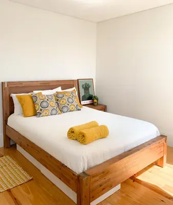 a bedroom with a wooden bed with yellow pillows at Guest House Arca de Água in Porto