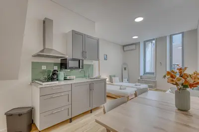 a kitchen with white cabinets and a living room at OPORTO GUEST Casa dos Clérigos in Porto
