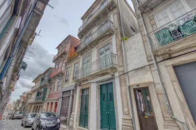 a building with green doors and cars parked on a street at OPORTO GUEST Casa dos Clérigos in Porto