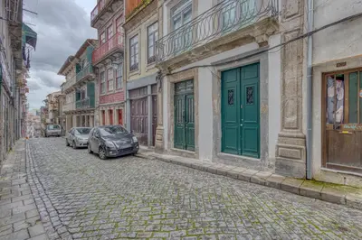 a cobblestone street with cars parked in front of buildings at OPORTO GUEST Casa dos Clérigos in Porto