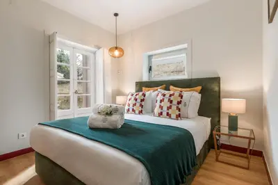 a bedroom with a large bed and two windows at Almada Charm Suites & Apartments in Porto