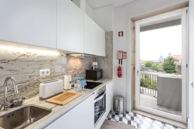 a white kitchen with a sink and a window at Alegria 283 in Porto