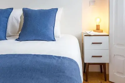 a bedroom with a bed with blue pillows and a night stand at Alegria 283 in Porto