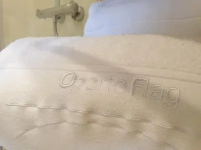 a bed with a white blanket with the word octoria flu on it at Oportoflag center in Porto