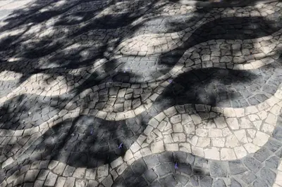 a cobblestone street with shadows of trees on it at FLH Porto City Mezzanine Apartment in Porto