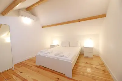 a white bedroom with a white bed and two lights at FLH Porto City Mezzanine Apartment in Porto
