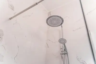 a shower head in a bathroom with white marble walls at River View Building in Vila Nova de Gaia