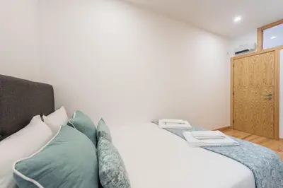 a white bed with green pillows in a room at LovelyStay - 1BR Flat w AC and Balcony by Aliados in Porto