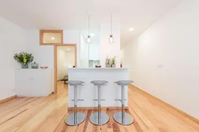 a kitchen with a white counter and stools at LovelyStay - 1BR Flat w AC and Balcony by Aliados in Porto