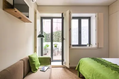 a bedroom with a bed and a couch and a window at Kings Oporto Apartments in Porto