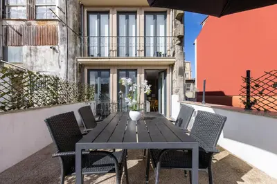 a wooden table with chairs and an umbrella on a balcony at Terrace Bliss with AC Downtown Porto in Porto