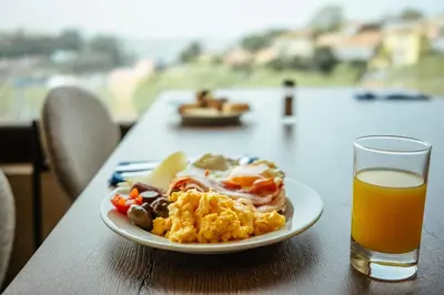 a plate of breakfast food and a glass of orange juice at Vilar Oporto Hotel in Porto