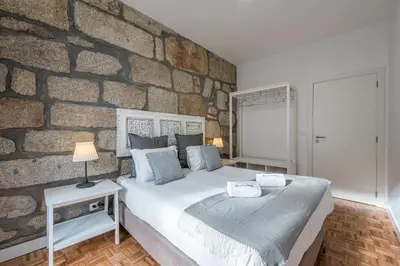a bed with a gray pillow and a table with a lamp at GuestReady - Grandeur River Balcony Reborn in Porto