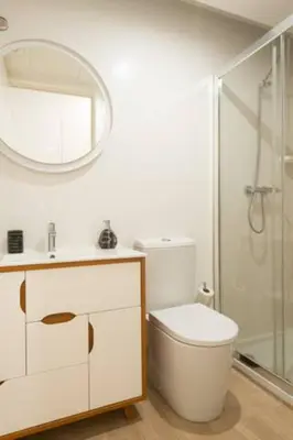 a white bathroom with a toilet and a mirror at Warmly Porto in Porto