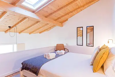 a bedroom with a white bed and wooden ceilings at Vila Burgães by LovelyStay in Porto