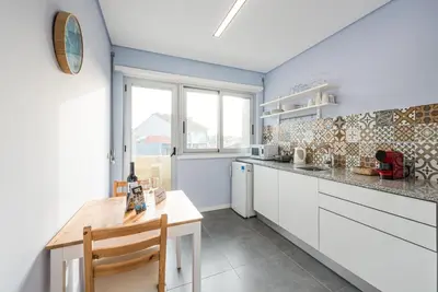 a kitchen with white cabinets and a wooden table at GuestReady - Wellspring Bloom in Porto