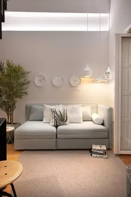 a living room with a couch and two clocks on the wall at Jasmine Loft in Porto
